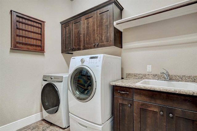 laundry area with a sink, baseboards, cabinet space, and washing machine and clothes dryer
