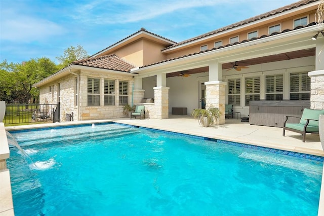 back of property with ceiling fan, a patio area, a tiled roof, and stone siding