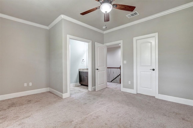 unfurnished bedroom featuring visible vents, crown molding, baseboards, carpet, and ensuite bath