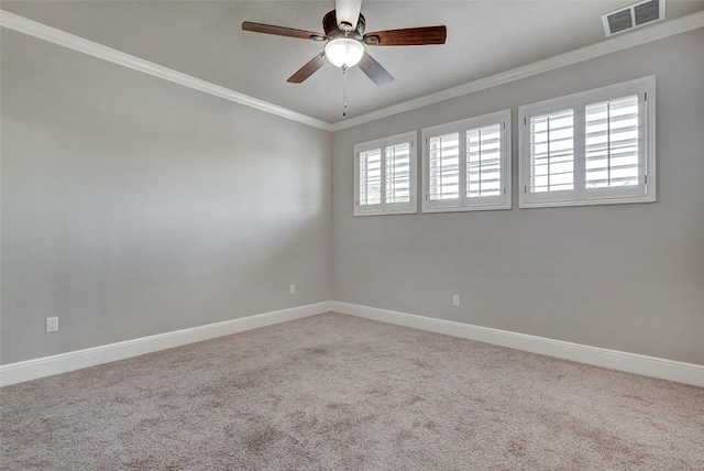 carpeted empty room with crown molding, baseboards, ceiling fan, and visible vents