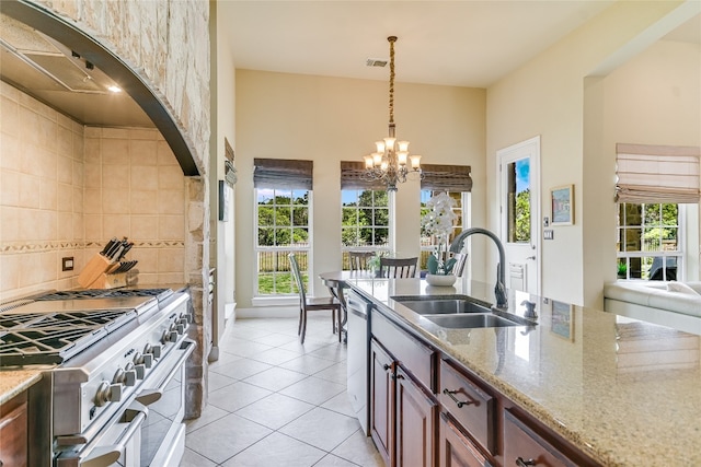 kitchen with light stone countertops, a chandelier, a sink, light tile patterned floors, and stainless steel appliances