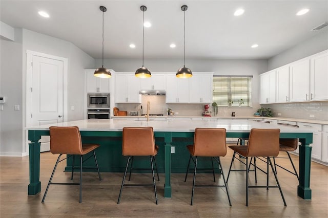 8600 Chrysler Bnd, Austin, TX 78744 - kitchen with appliances with stainless steel finishes, backsplash, white cabinetry, a large island with sink, and light countertops
