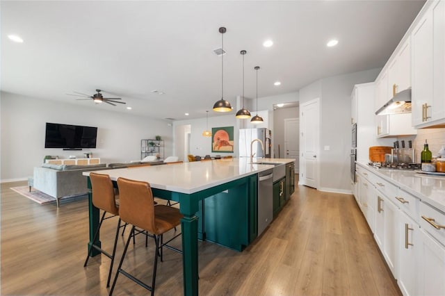 8600 Chrysler Bnd, Austin, TX 78744 - kitchen featuring under cabinet range hood, a ceiling fan, white cabinetry, a large island, and recessed lighting