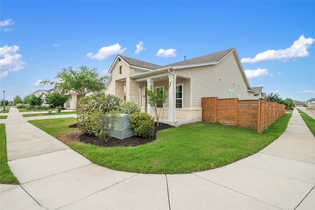 8600 Chrysler Bnd, Austin, TX 78744 - view of side of property with a lawn, fence, a shingled roof, and stone siding