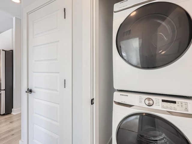 washroom with baseboards, laundry area, light wood-style flooring, and stacked washer / dryer