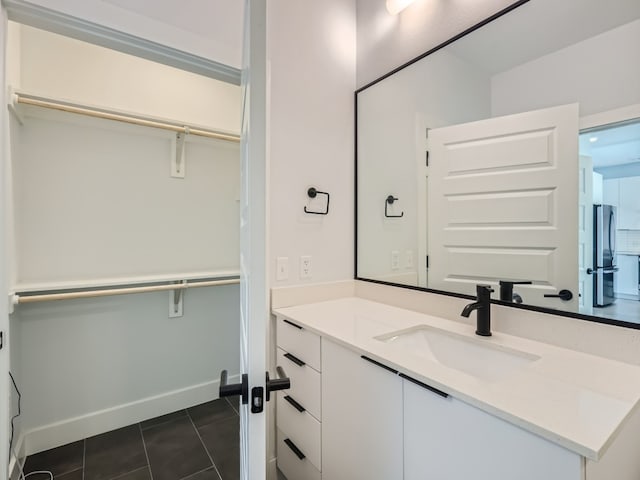bathroom with vanity, baseboards, tile patterned floors, and a spacious closet