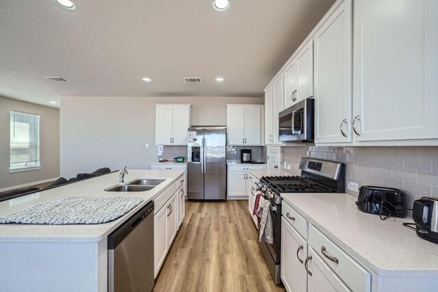 kitchen featuring a sink, backsplash, stainless steel appliances, and visible vents