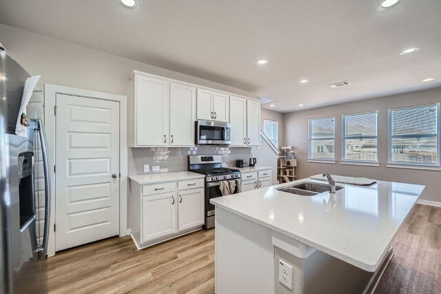 kitchen featuring a sink, appliances with stainless steel finishes, light wood-style floors, and visible vents
