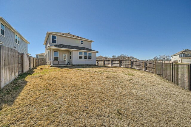 rear view of house with a yard, a fenced backyard, and stucco siding