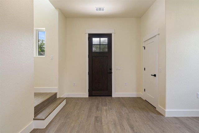 entrance foyer with baseboards, stairs, wood finished floors, and visible vents