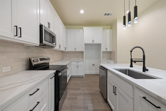 1000 Vargas Rd Unit A, Austin, TX 78741 - kitchen with stainless steel appliances, light stone countertops, white cabinetry, decorative backsplash, and pendant lighting