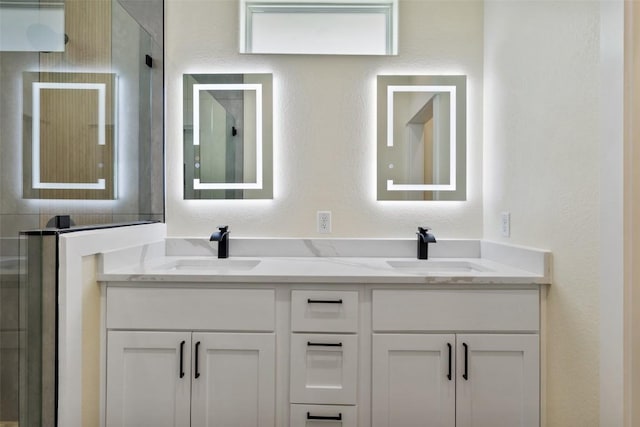 bathroom featuring a sink, a shower with door, and double vanity