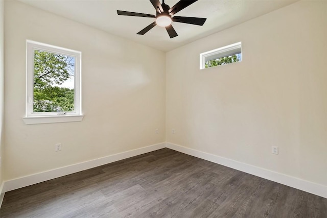 unfurnished room featuring baseboards, dark wood finished floors, and plenty of natural light