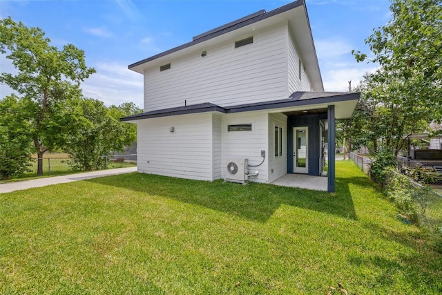 back of property with ac unit, fence, and a yard
