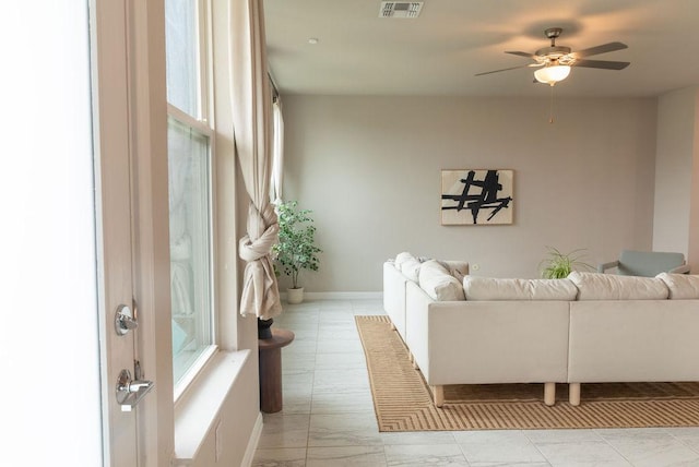 living area with a ceiling fan, baseboards, visible vents, and marble finish floor