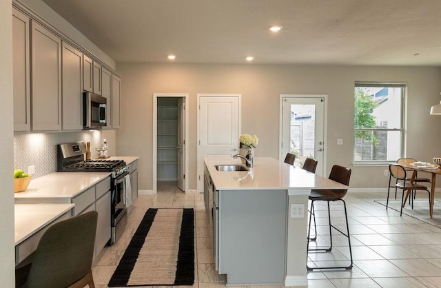kitchen featuring gray cabinetry, appliances with stainless steel finishes, baseboards, and a sink