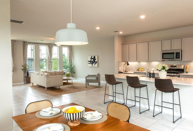kitchen featuring visible vents, light countertops, stainless steel appliances, decorative backsplash, and gray cabinetry
