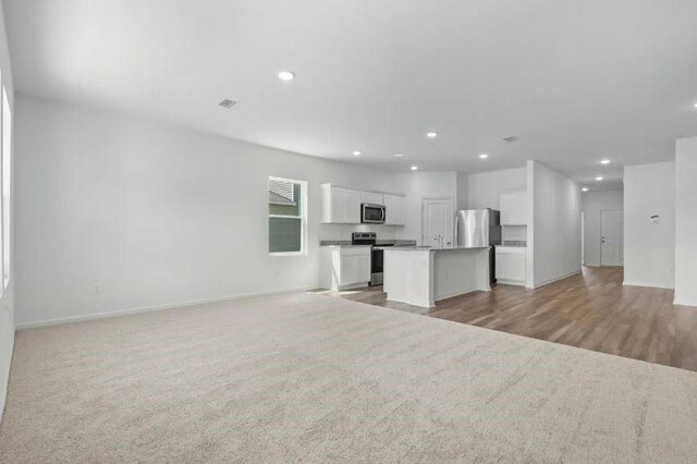unfurnished living room with baseboards, recessed lighting, light wood-style flooring, and visible vents