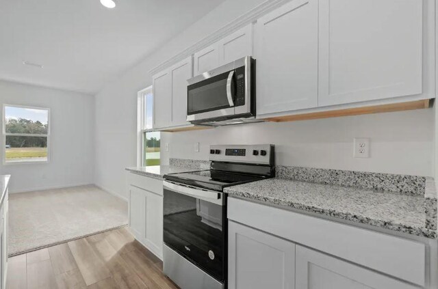 kitchen with light wood-style floors, white cabinetry, appliances with stainless steel finishes, and a healthy amount of sunlight