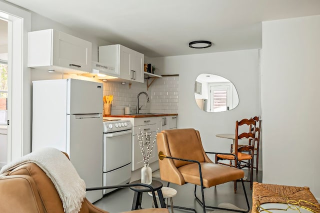 kitchen with backsplash, range hood, a sink, white appliances, and white cabinetry