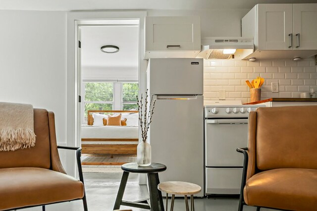 1613 Garden St, Austin, TX 78702 - kitchen featuring freestanding refrigerator, under cabinet range hood, electric range, decorative backsplash, and concrete floors