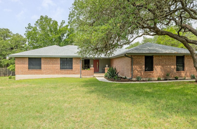 single story home featuring brick siding, roof with shingles, and a front yard