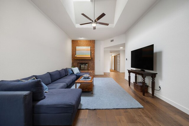 living area with ceiling fan, visible vents, a brick fireplace, wood finished floors, and lofted ceiling