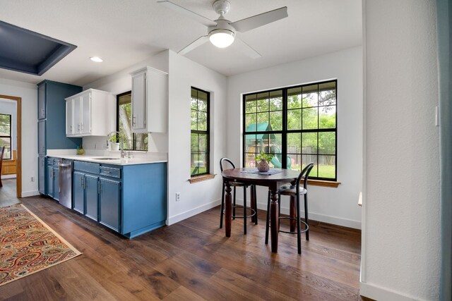 kitchen featuring a sink, dishwasher, light countertops, baseboards, and blue cabinets