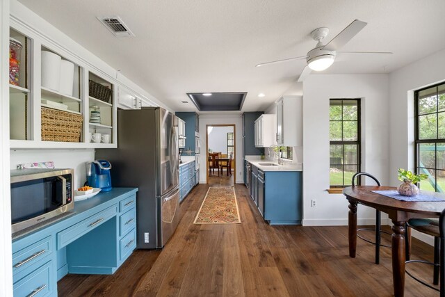 kitchen featuring white cabinets, light countertops, dark wood finished floors, stainless steel appliances, and visible vents