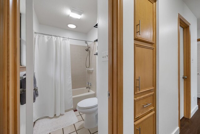 full bathroom featuring toilet, tile patterned floors, and shower / bath combination with curtain