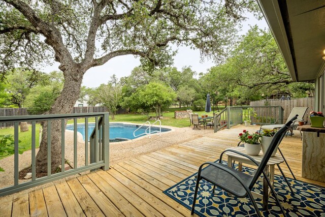 view of swimming pool with a fenced in pool, a wooden deck, a fenced backyard, and outdoor dining space
