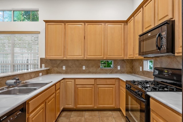 kitchen with a sink, light countertops, decorative backsplash, light tile patterned floors, and black appliances
