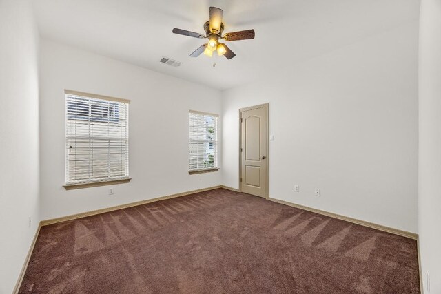 carpeted empty room featuring visible vents, a ceiling fan, and baseboards