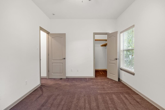 unfurnished bedroom featuring baseboards, carpet, and a walk in closet