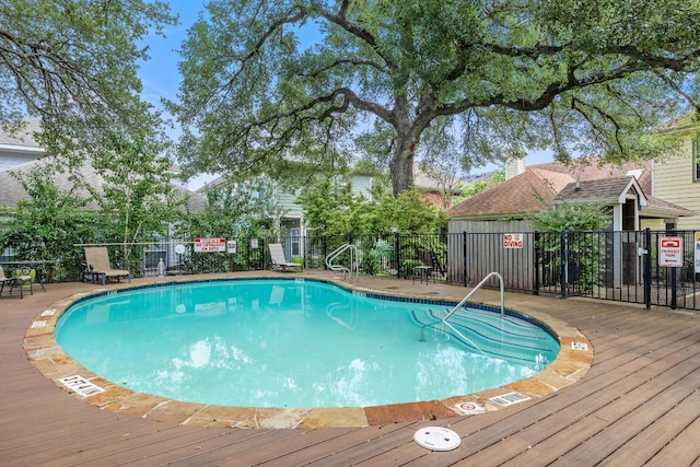 community pool featuring fence and a wooden deck
