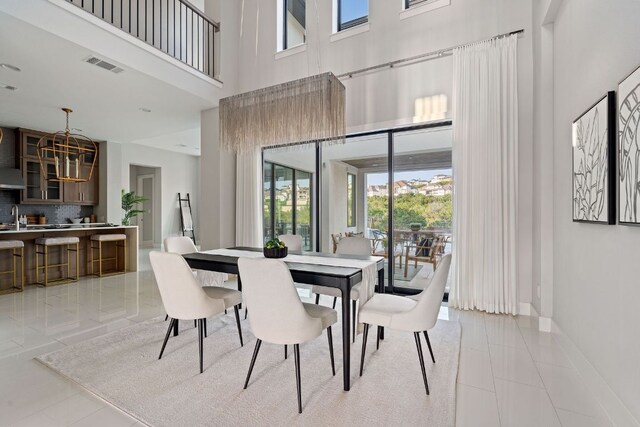 dining area featuring light tile patterned floors, a high ceiling, plenty of natural light, and visible vents