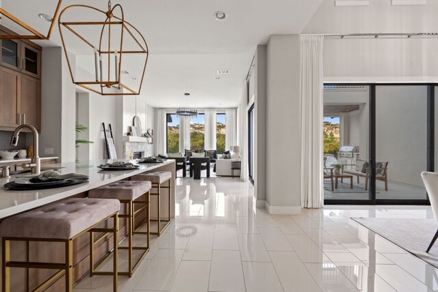 kitchen with light tile patterned floors, an inviting chandelier, glass insert cabinets, and a wealth of natural light