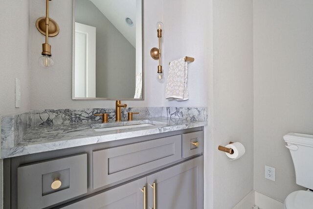 bathroom featuring vanity, vaulted ceiling, and toilet