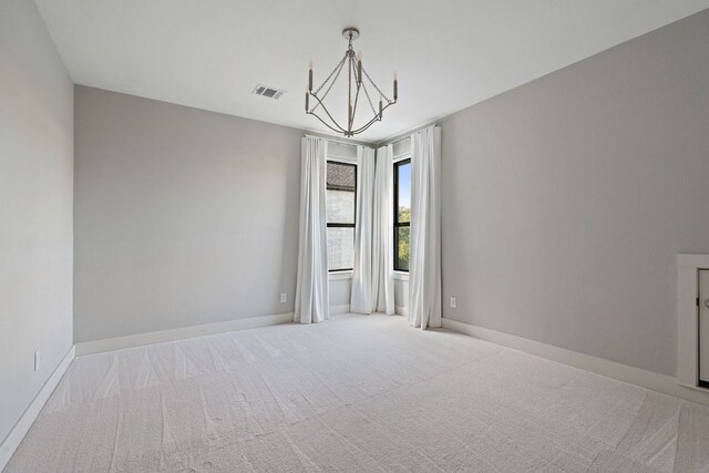 empty room featuring visible vents, carpet, baseboards, and a chandelier