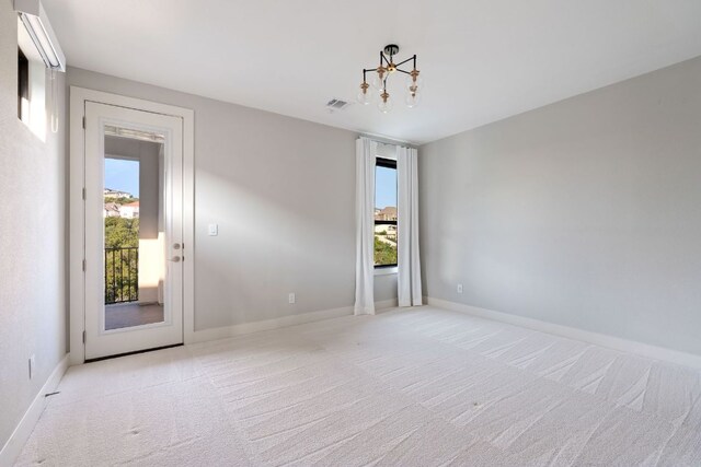 empty room with baseboards, visible vents, a chandelier, and light colored carpet