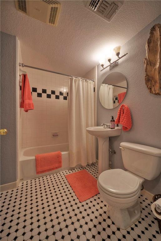 bathroom featuring toilet, a textured ceiling, visible vents, and shower / bath combo