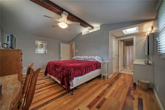 bedroom with visible vents, light wood-style floors, baseboards, vaulted ceiling with skylight, and a ceiling fan