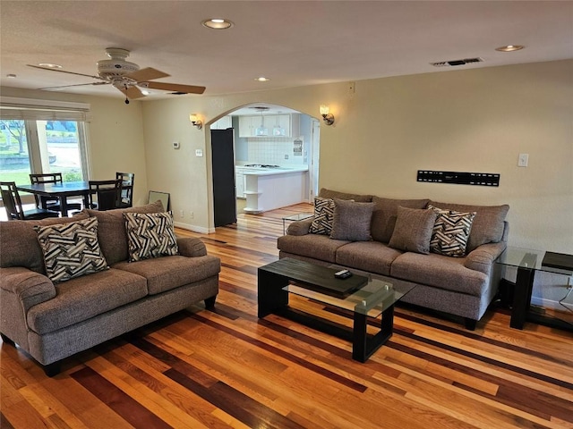 living room with visible vents, a ceiling fan, wood finished floors, recessed lighting, and arched walkways