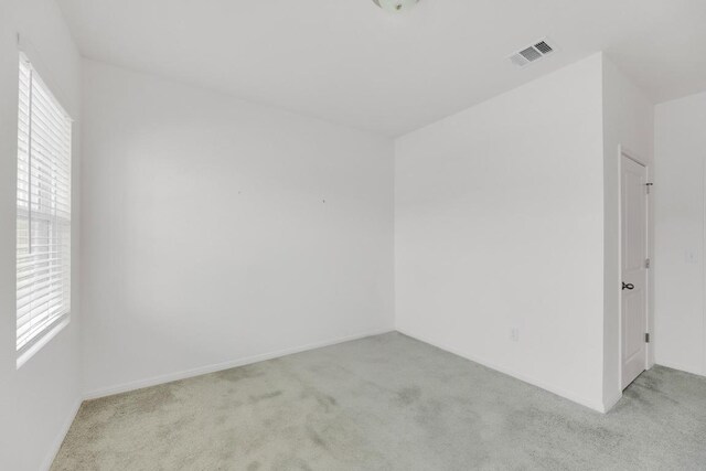 carpeted spare room featuring visible vents and baseboards