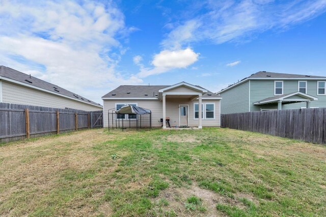 rear view of property with a fenced backyard and a lawn