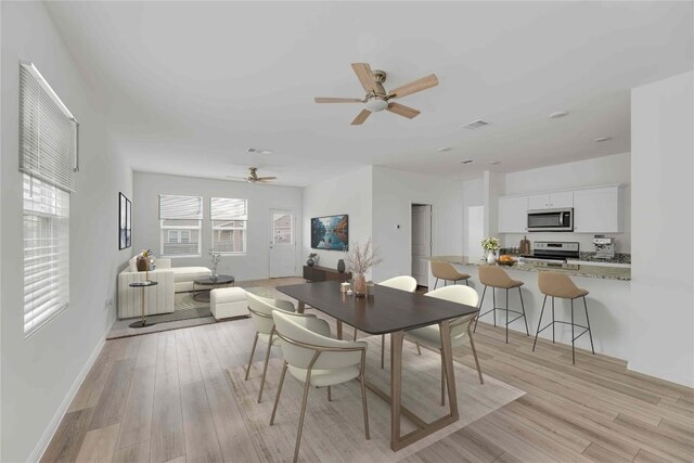 dining area featuring a ceiling fan, baseboards, visible vents, and light wood finished floors