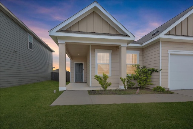 exterior entry at dusk featuring a garage, board and batten siding, and a yard