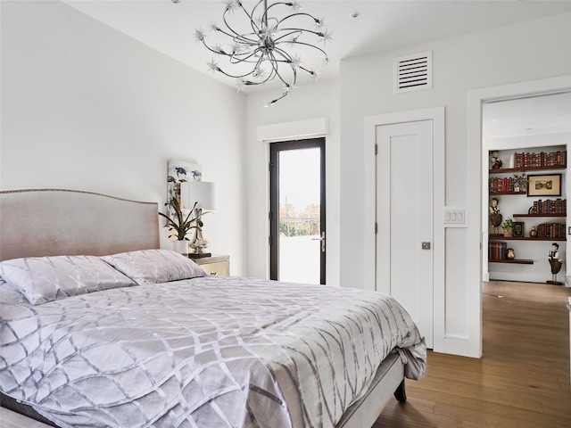 bedroom featuring an inviting chandelier, wood finished floors, and visible vents