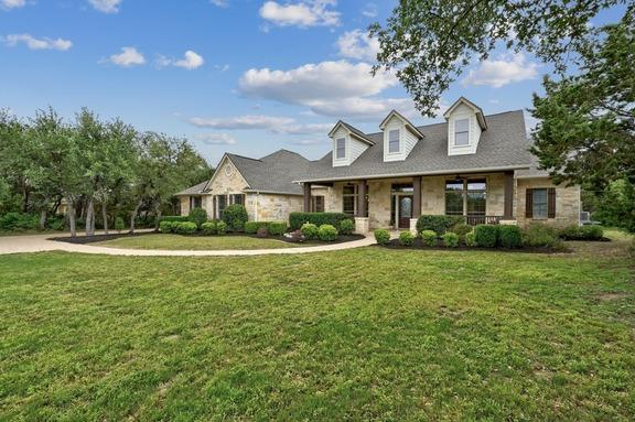 view of front of house featuring covered porch, stone siding, and a front yard