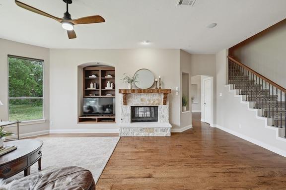 living room with visible vents, wood finished floors, baseboards, stairway, and a ceiling fan